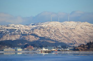 Coast Guard base Kodiak is seen across Women's Bay. Atop Pillar Mountain, beyond the base, are three wind turbines operated by Kodiak Electric Association. Photo by James Brooks. CC BY 2.0.