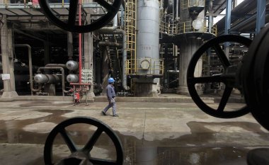 A worker walks past oil pipes at a refinery in Wuhan, Hubei province in this March 23, 2012 file photo. China is expected to report commodities output data on November 11, 2015.  REUTERS/Stringer/FilesTHE ASIA FILE - NOV 11 2015