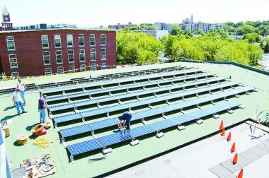 Workers install solar panels on the roof of a building in Franklin. (Leigh Sharps / for the Citizen