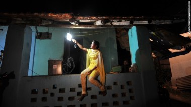 A woman turns on a solar-powered light at her home near Mumbai.