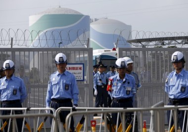 Police officers and security personnel stand guard at an entrance of Kyushu Electric Power's Sendai nuclear power station, during a protest. Photo by Issei Kato / Reuters.
